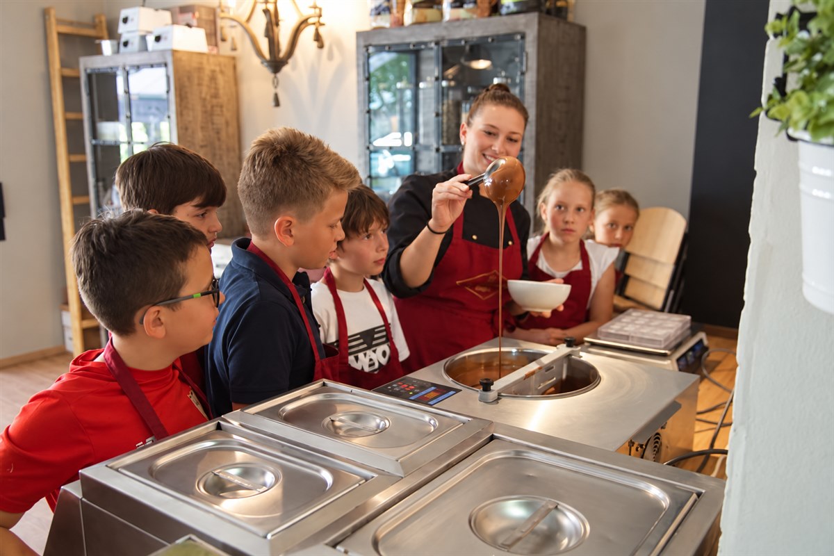 Kinder beobachten, wie eine Kursleiterin flüssige Schokolade vorführt.